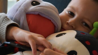 Un garçon allongé en arrière sert contre lui Kimochis Huggiotpus et Kimochis Bug